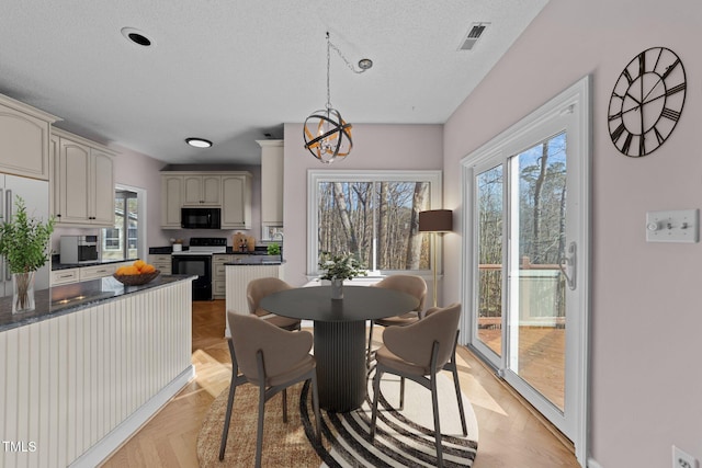 dining room with plenty of natural light, visible vents, a chandelier, and a textured ceiling