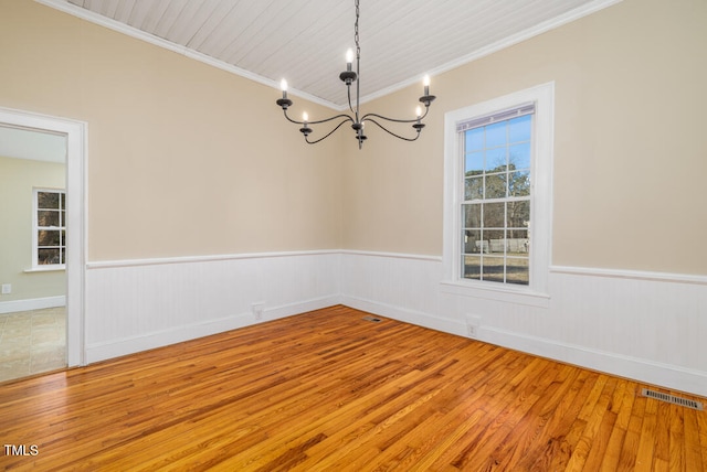 empty room with crown molding, wood-type flooring, and a chandelier