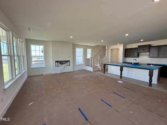 unfurnished living room with stairs, plenty of natural light, and recessed lighting