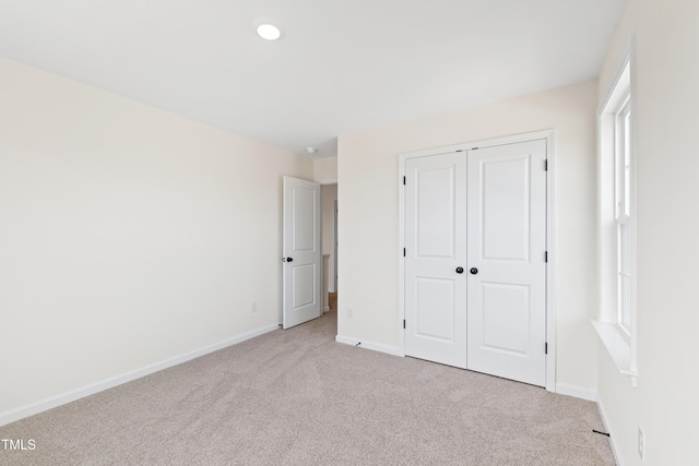 unfurnished bedroom featuring light carpet and a closet