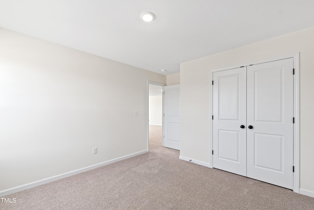 unfurnished bedroom with light colored carpet and a closet