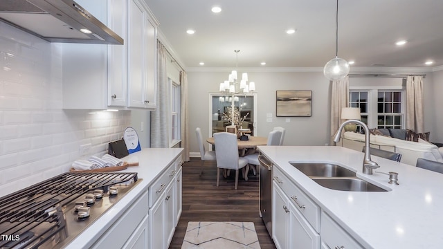 kitchen with sink, range hood, stainless steel appliances, white cabinets, and decorative light fixtures