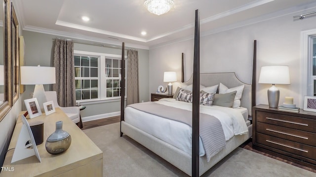 bedroom with a raised ceiling, crown molding, and light wood-type flooring