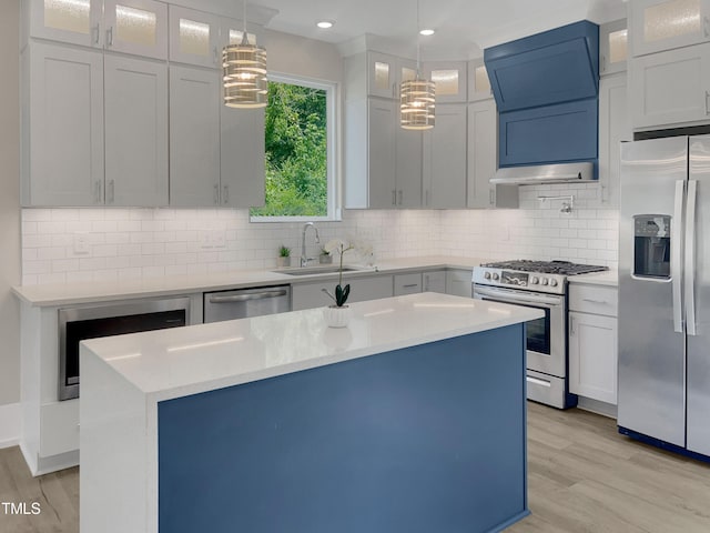 kitchen with stainless steel appliances, a kitchen island, sink, and hanging light fixtures