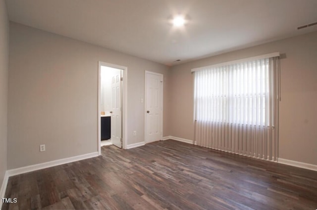 unfurnished bedroom featuring dark wood-type flooring and connected bathroom