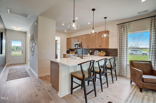 kitchen with pendant lighting, sink, appliances with stainless steel finishes, light brown cabinetry, and kitchen peninsula