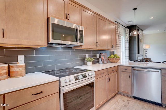 kitchen with decorative light fixtures, light brown cabinets, appliances with stainless steel finishes, light hardwood / wood-style floors, and decorative backsplash