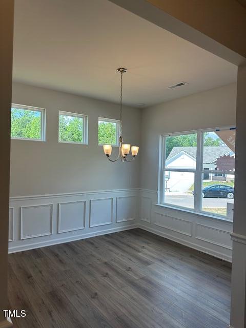 142 Vega Loop, Sanford, NC 27330 - unfurnished dining area with a chandelier, a decorative wall, a wainscoted wall, and dark wood-style floors