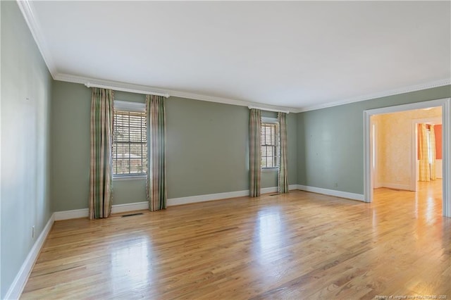 spare room with crown molding, a healthy amount of sunlight, and light hardwood / wood-style floors