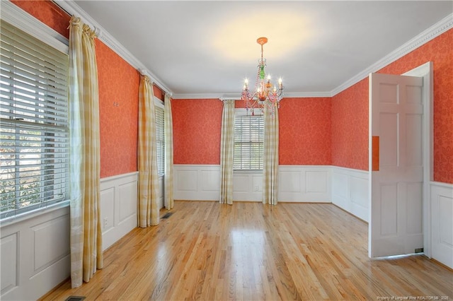 unfurnished dining area featuring crown molding, light hardwood / wood-style floors, and a chandelier