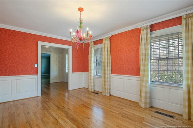 unfurnished room featuring hardwood / wood-style floors, crown molding, and a chandelier