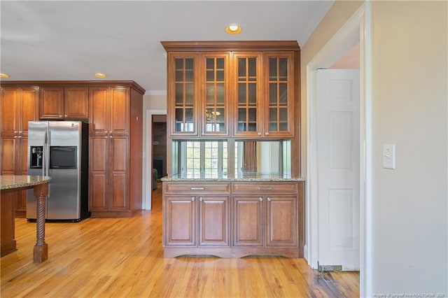 kitchen with light stone counters, stainless steel fridge, and light hardwood / wood-style flooring