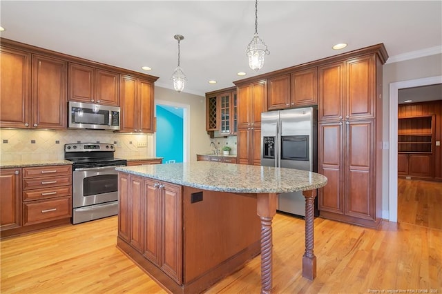 kitchen featuring a kitchen island, decorative light fixtures, a kitchen breakfast bar, light stone counters, and stainless steel appliances