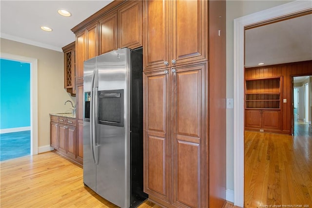 kitchen with stainless steel fridge, ornamental molding, light hardwood / wood-style floors, light stone countertops, and built in shelves