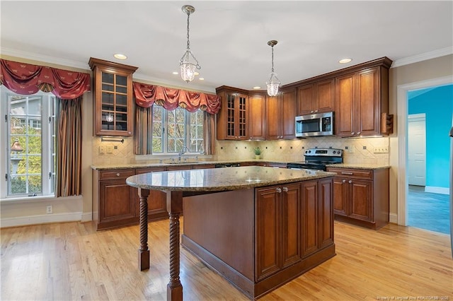 kitchen featuring appliances with stainless steel finishes, decorative light fixtures, sink, a center island, and light stone countertops