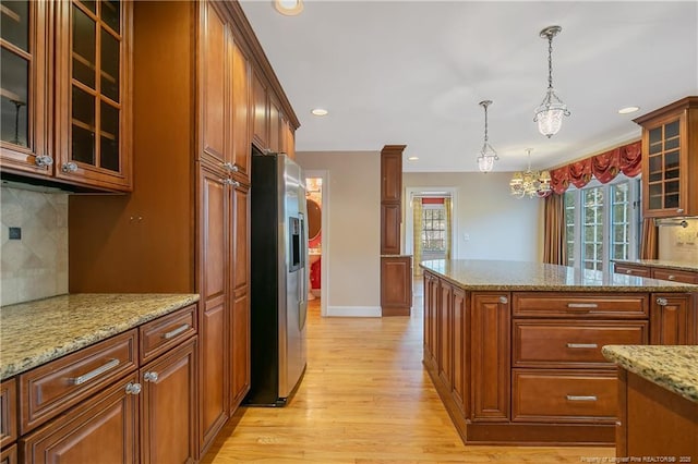 kitchen with tasteful backsplash, stainless steel fridge with ice dispenser, light hardwood / wood-style flooring, pendant lighting, and light stone countertops