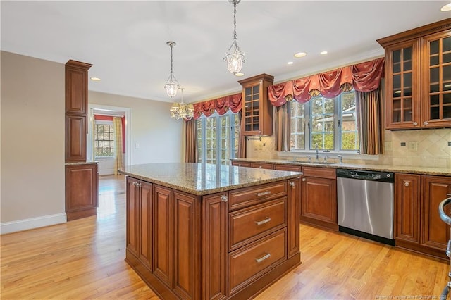 kitchen featuring sink, a center island, stainless steel dishwasher, pendant lighting, and light hardwood / wood-style floors