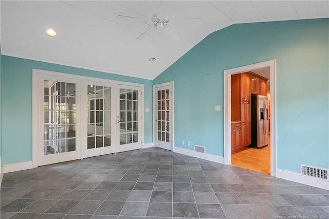 empty room with lofted ceiling, dark tile patterned floors, french doors, and ceiling fan