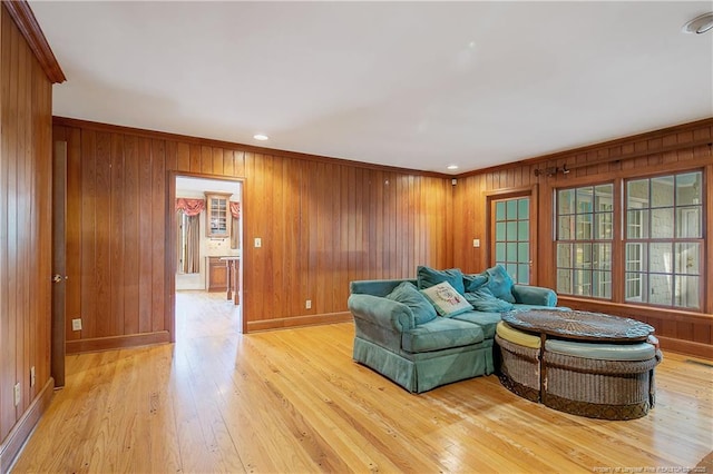 living room featuring ornamental molding, wooden walls, and light wood-type flooring