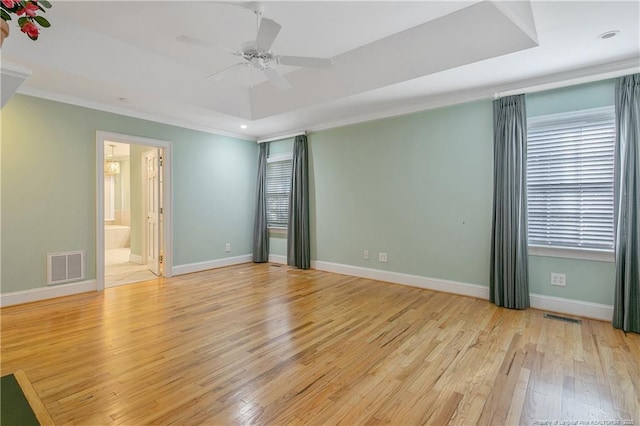 unfurnished room with a raised ceiling, ceiling fan, crown molding, and light hardwood / wood-style floors