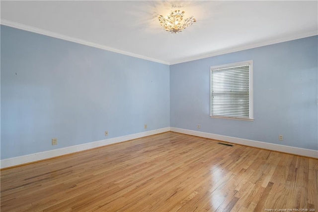 empty room with ornamental molding and light wood-type flooring