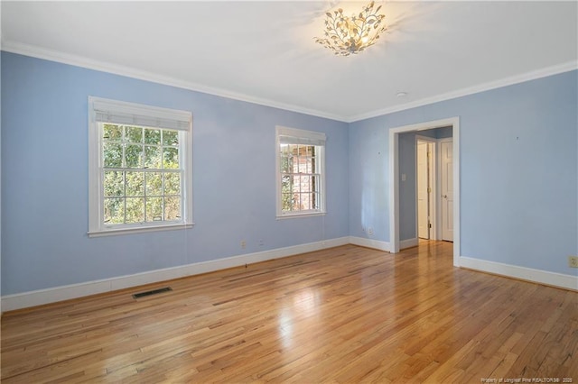 empty room with ornamental molding and light hardwood / wood-style floors