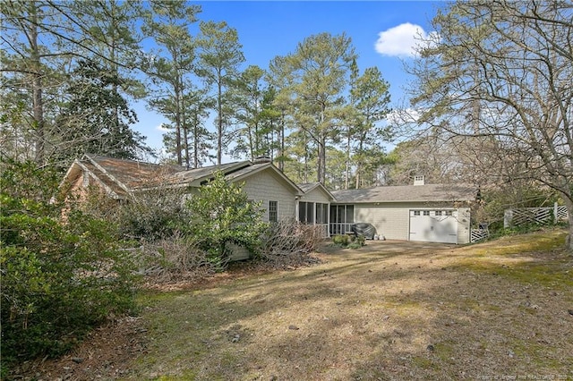 rear view of house featuring a garage, a lawn, and a sunroom