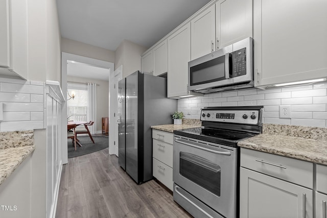 kitchen featuring tasteful backsplash, appliances with stainless steel finishes, light stone countertops, and white cabinets