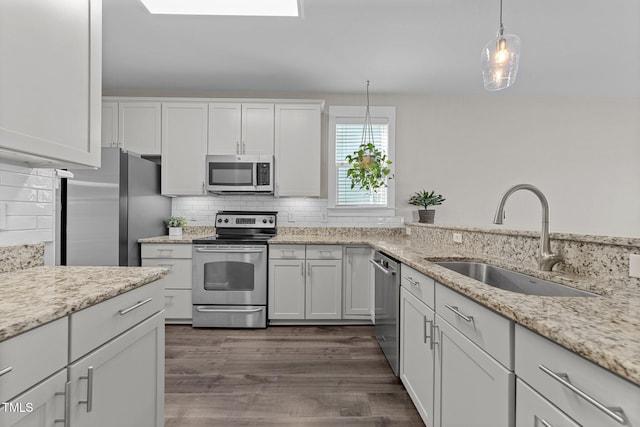 kitchen with white cabinetry, appliances with stainless steel finishes, sink, and decorative light fixtures