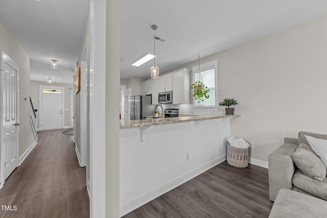 kitchen featuring a breakfast bar, white cabinetry, appliances with stainless steel finishes, kitchen peninsula, and pendant lighting