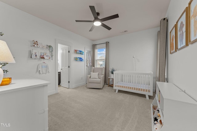 carpeted bedroom with ceiling fan and a crib