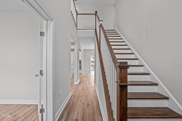 stairway featuring a towering ceiling and wood-type flooring