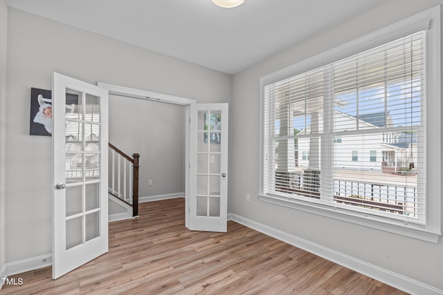 empty room with light hardwood / wood-style floors and french doors