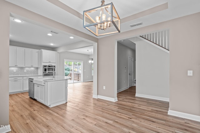 kitchen featuring decorative light fixtures, white cabinetry, a chandelier, decorative backsplash, and light wood-type flooring