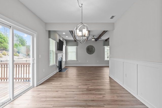 unfurnished dining area featuring light wood-type flooring and a notable chandelier