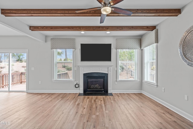 unfurnished living room with beamed ceiling, a healthy amount of sunlight, and light wood-type flooring