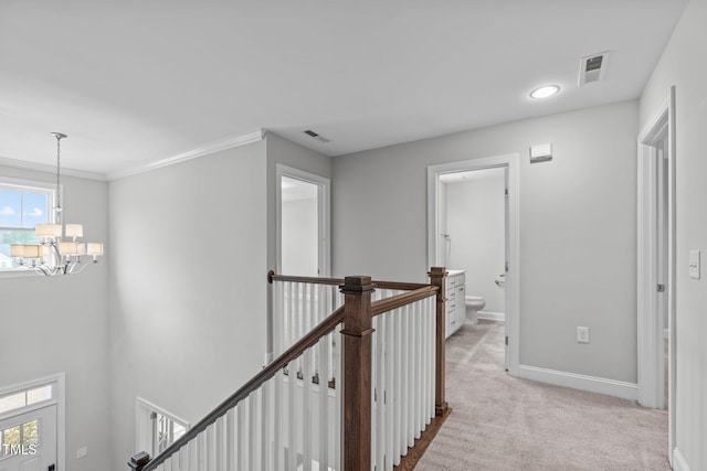 hall with ornamental molding, light carpet, and a notable chandelier