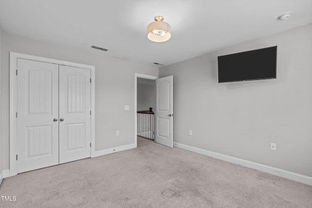 unfurnished bedroom featuring light colored carpet and a closet