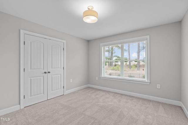 unfurnished bedroom with light colored carpet and a closet