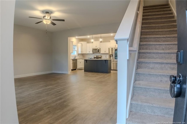 staircase with ceiling fan, wood-type flooring, and sink