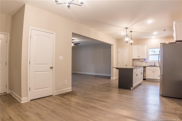 kitchen with pendant lighting, appliances with stainless steel finishes, white cabinetry, a center island, and wood-type flooring