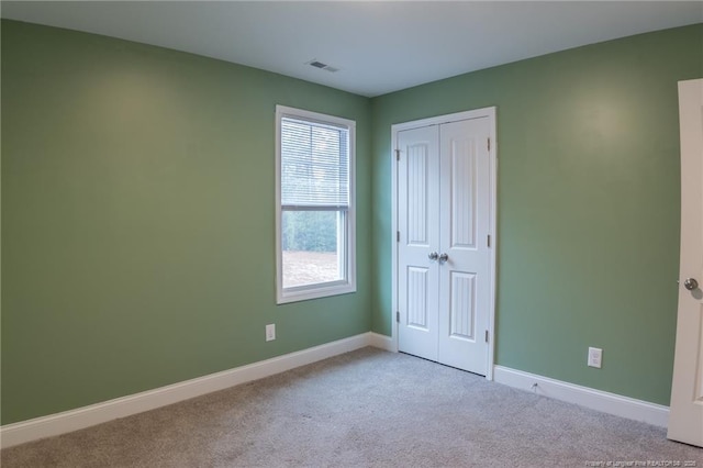 unfurnished bedroom featuring a closet and light carpet