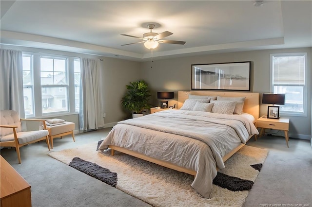 carpeted bedroom with ceiling fan and a raised ceiling