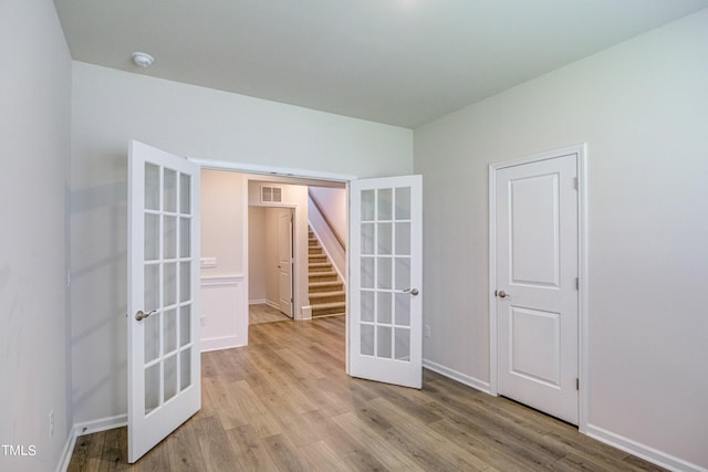 spare room with french doors and light hardwood / wood-style floors