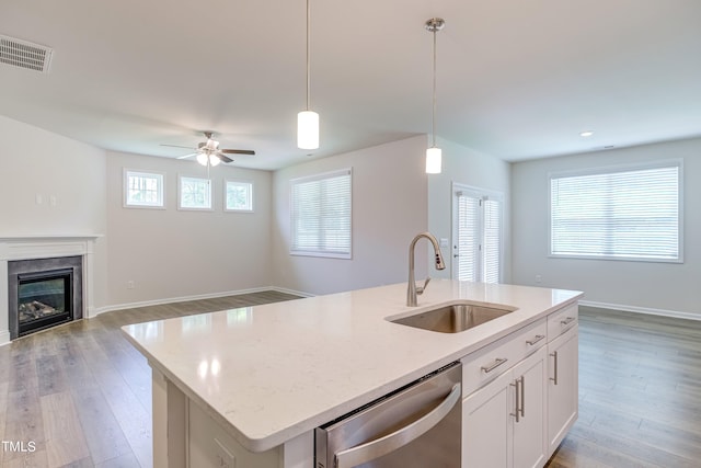 kitchen with sink, white cabinets, hanging light fixtures, a kitchen island with sink, and stainless steel dishwasher