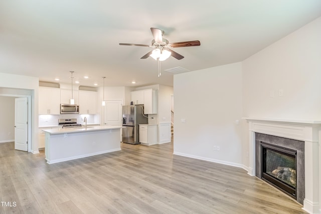 kitchen featuring pendant lighting, an island with sink, white cabinets, and appliances with stainless steel finishes