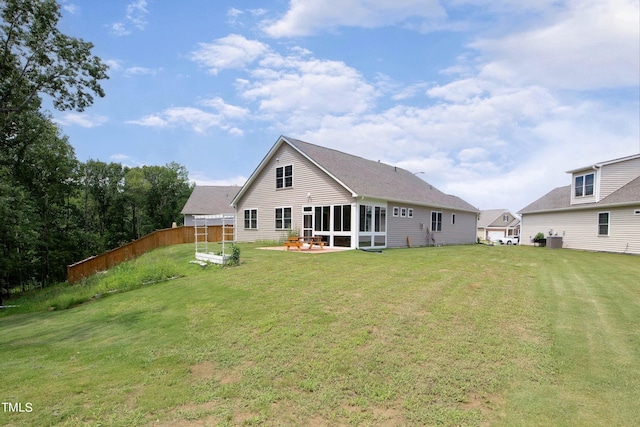 rear view of property featuring a sunroom, a yard, and a patio area