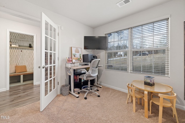 office with carpet flooring and french doors