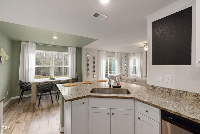 kitchen with sink, white cabinetry, hardwood / wood-style floors, light stone counters, and stainless steel dishwasher