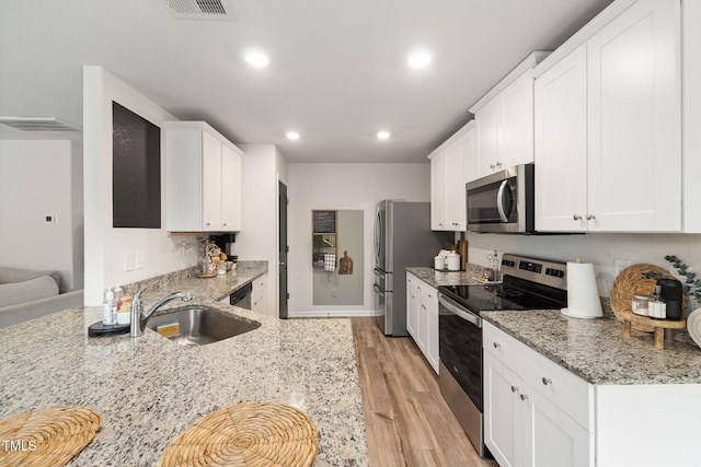 kitchen featuring appliances with stainless steel finishes, light stone countertops, and white cabinets